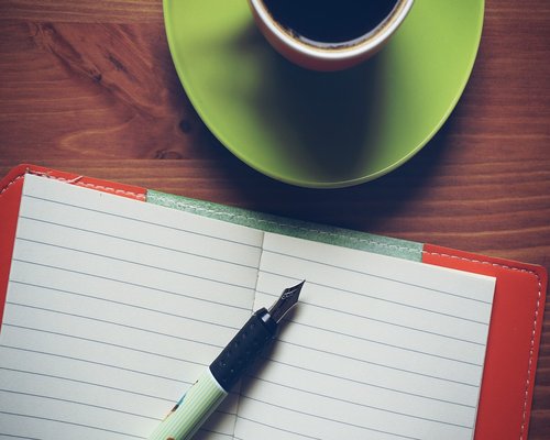 Notepad and pen for writing health questions on a wooden desk